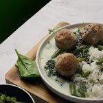 A savory dish of meatballs, rice, and green beans on a decorative plate.